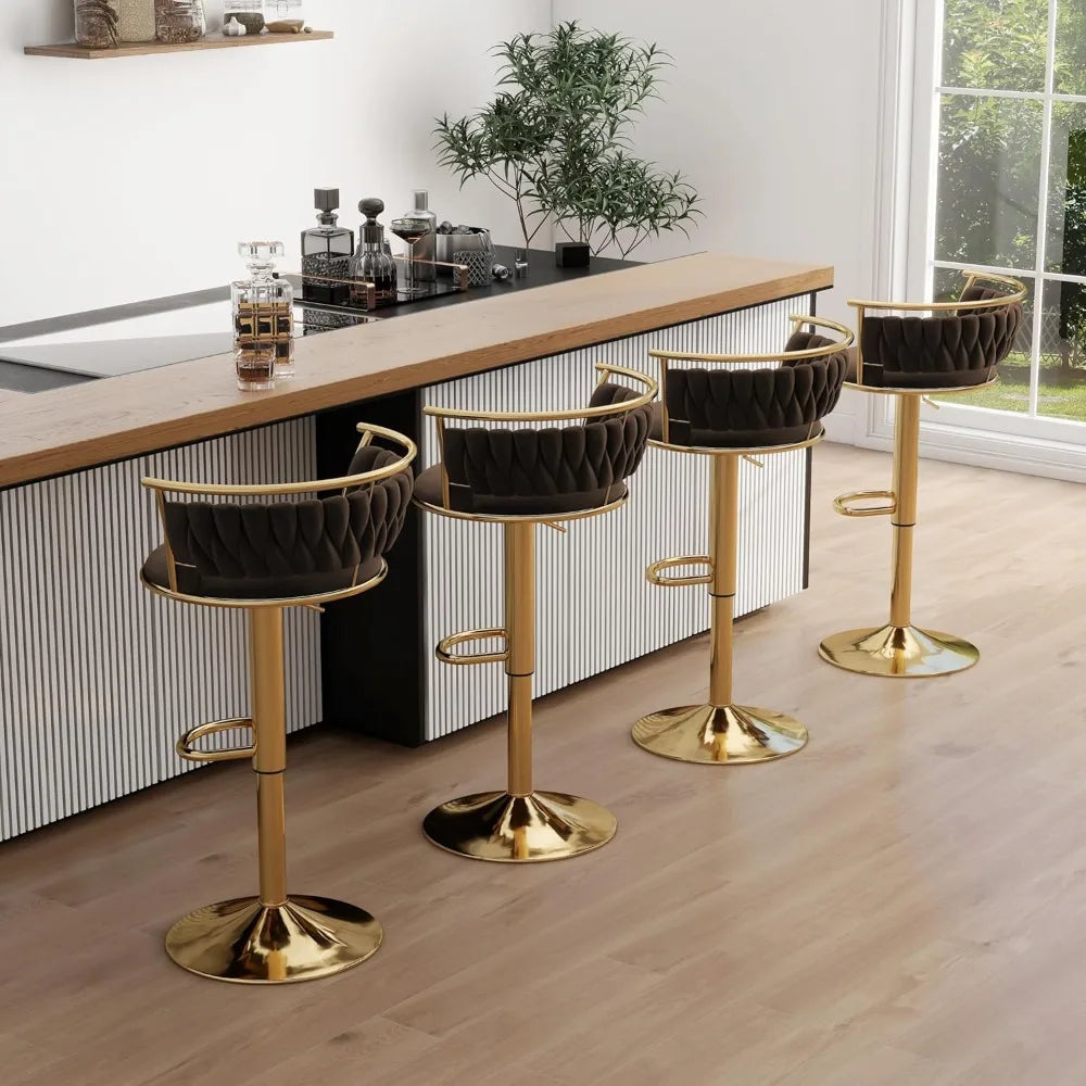 Four bar stools with gold legs and black seats in a modern kitchen setting.